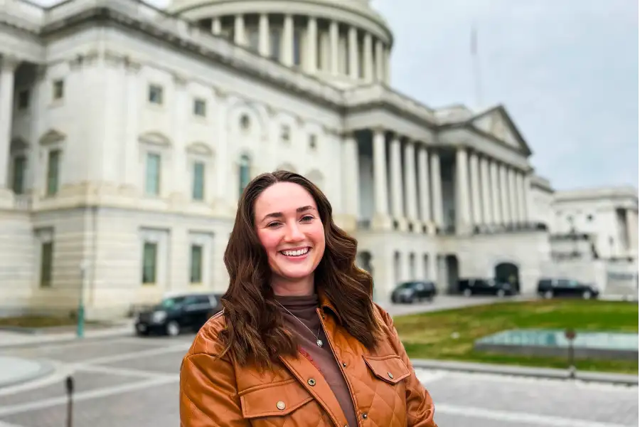 A smiling woman in front of the US Capitol building.