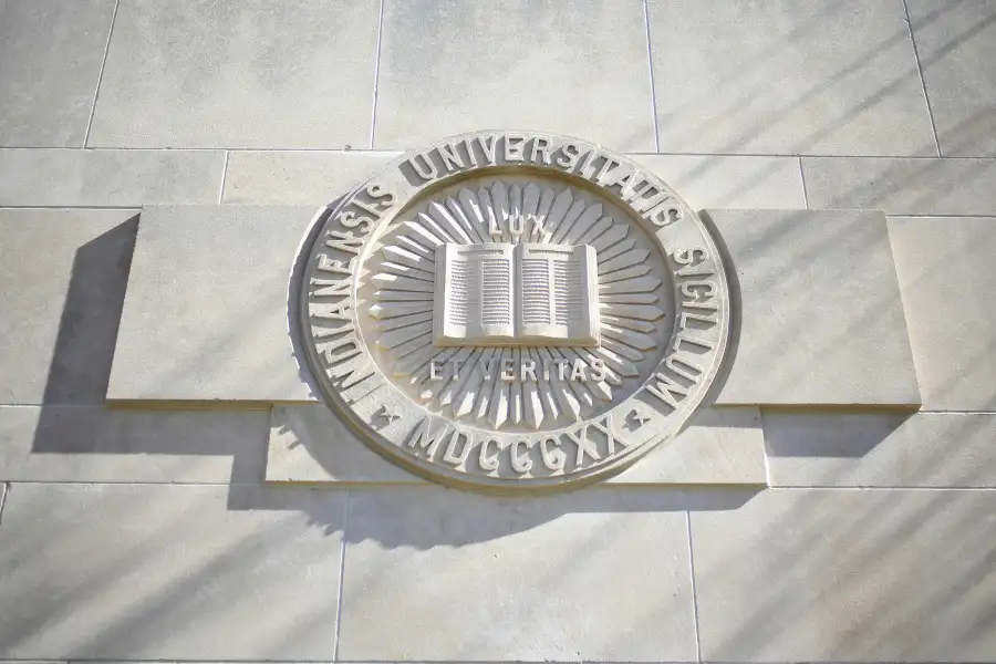 The Indiana University Seal carved in limestone and dramatically lit.