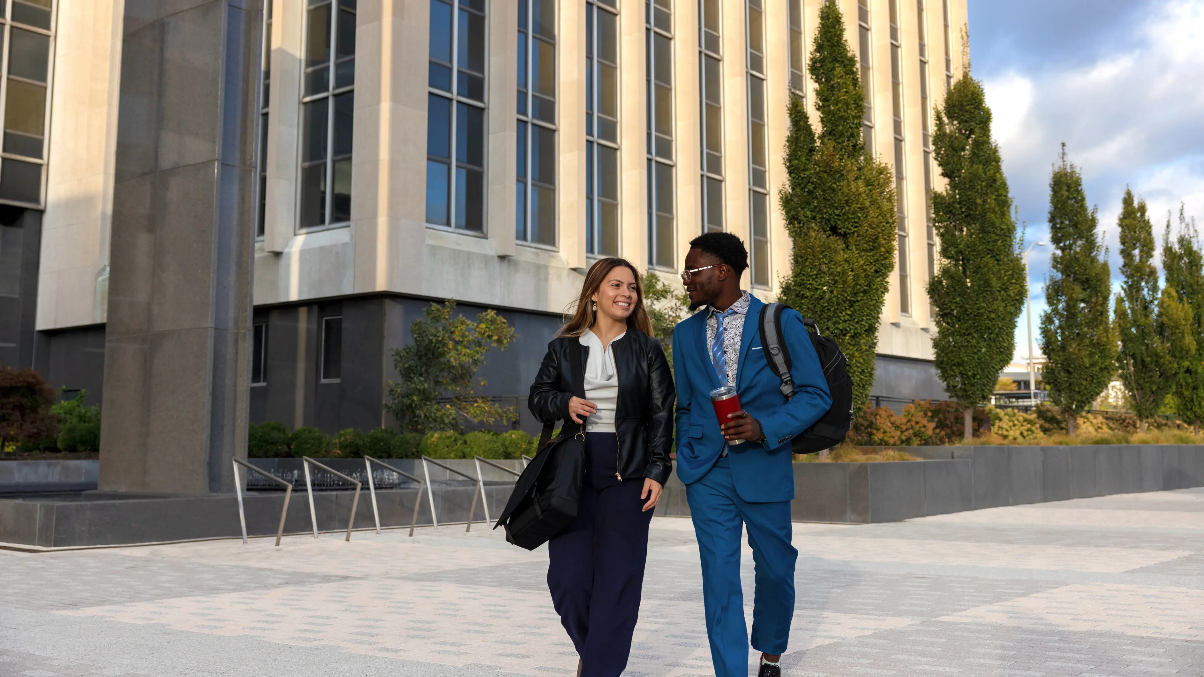 Two students walk on campus while in conversation.